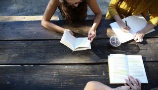 A reading group outdoors at a picnic table